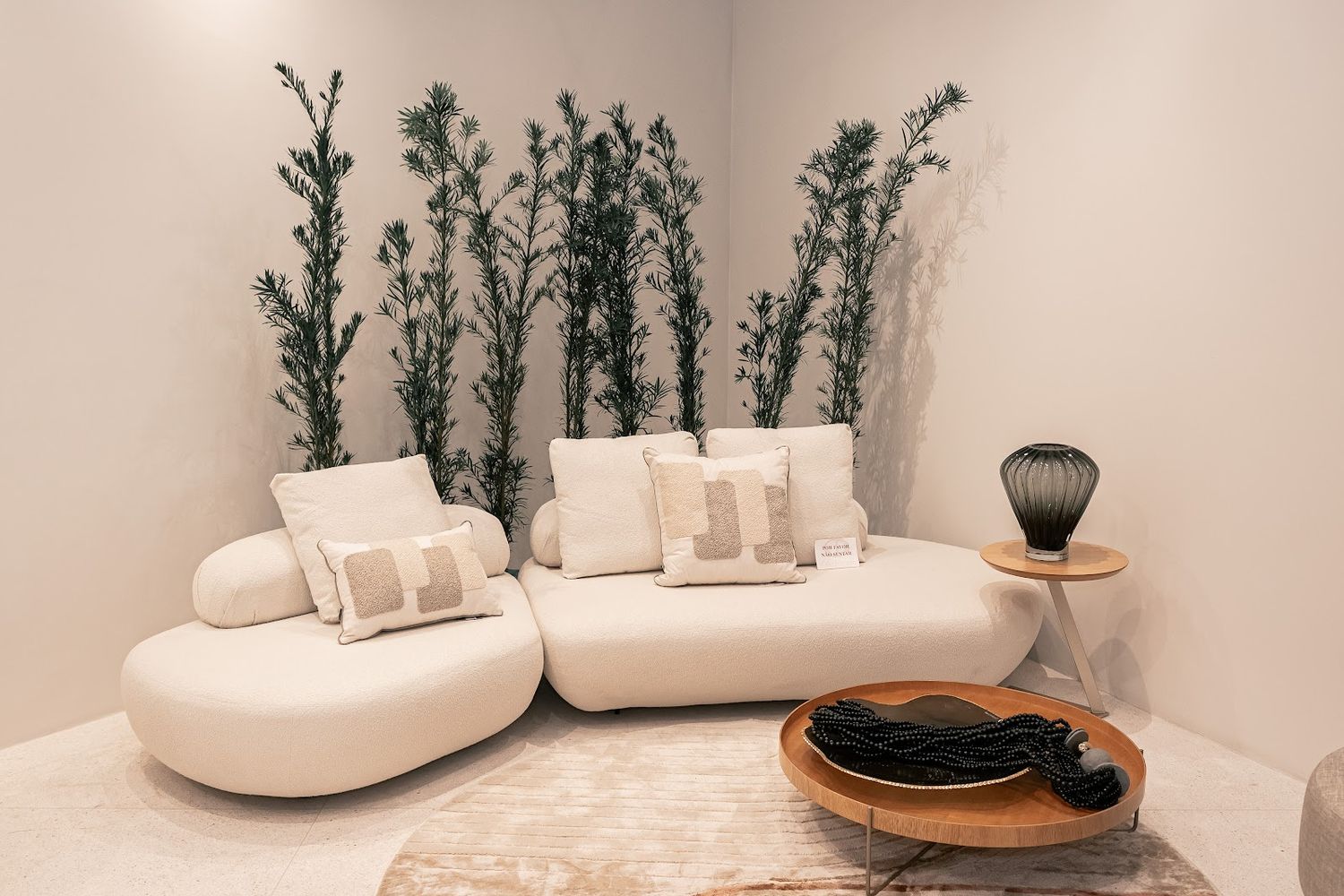 Sofá curvo em bouclê com plantas no showroom da La Decor
