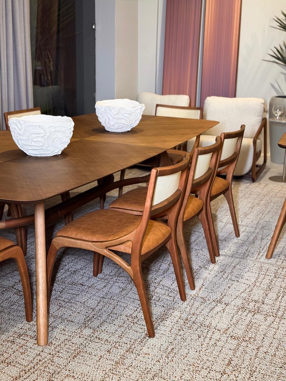 Mesa de jantar em madeira com cadeiras de couro no showroom da La Decor